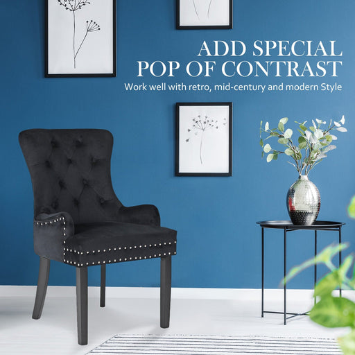 The La Bella Velvet Black French Provincial Dining Chair in an indoor setting, resting next to a side table and vase on a white floor in front of a blue wall containing 3 picture frames in the background