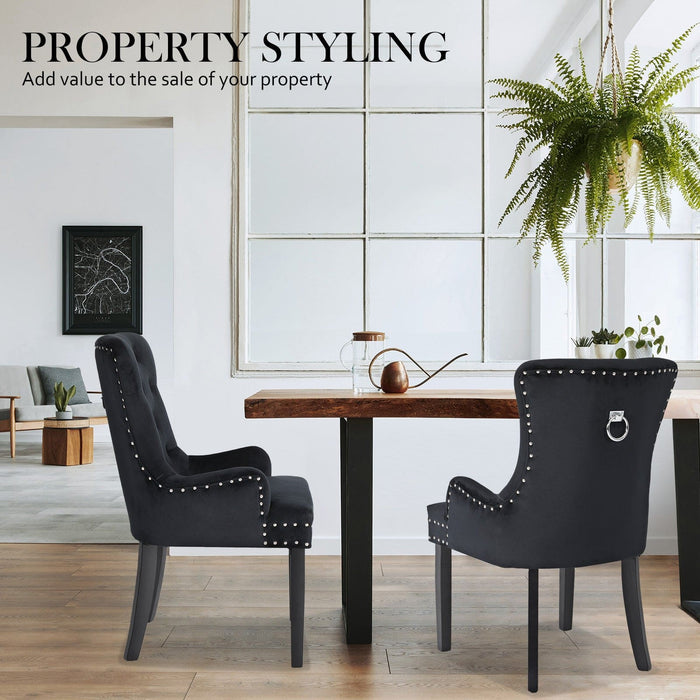 The La Bella Velvet Black French Provincial Dining Chair set in an indoor setting, around a coffee table resting on a timber floor, in front of a white wall with a large window. A lounge room off to the side on the left.