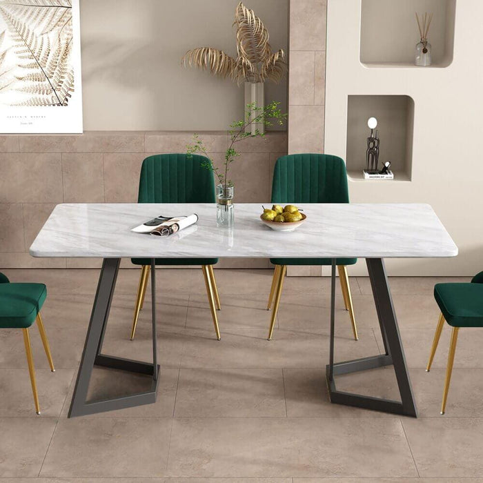 The Rectangular Marble-Effect Dining Table in an Indoor Setting with 4 Green chairs set around. A vase and flower, magazine and bowl of fruit resting on the table top